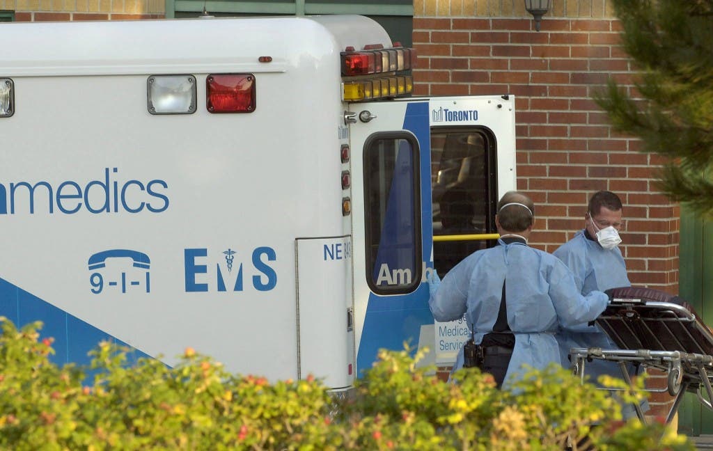 TORONTO (CANADA), Unos paramédicos de Toronto llevando vestidos quirúrgicos y máscaras sacan de una ambulancia a una mujer anciana de la casa "Seven Oaks" hacia el hospital hoy, miércoles 5 de octubre. Desde la última semana de septiembre, 16 personas han muerto en casas de ancianos como consecuencia de un brote de una enferemedad respiratoria no identificada. Ochenta y ocho personas han sido afectadas por esta enfermedad desconocida y 38 permanecen en el hospital. No hay evidencias de que el seudogripe se haya extendido más allá de la residencia.