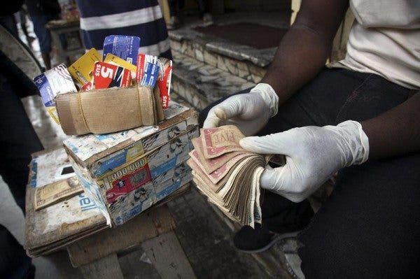 En la foto se ve las manos de un vendedor ambulante con guantes de plástico con los que cuenta billetes