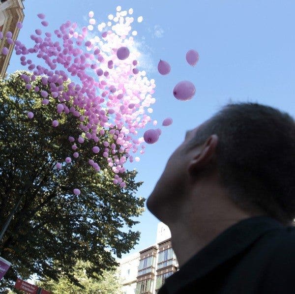 Un hombre mira la los globos rosas que vuelan en el cielo de la ciudad, como símbolo de la lucha contra el cáncer de mama