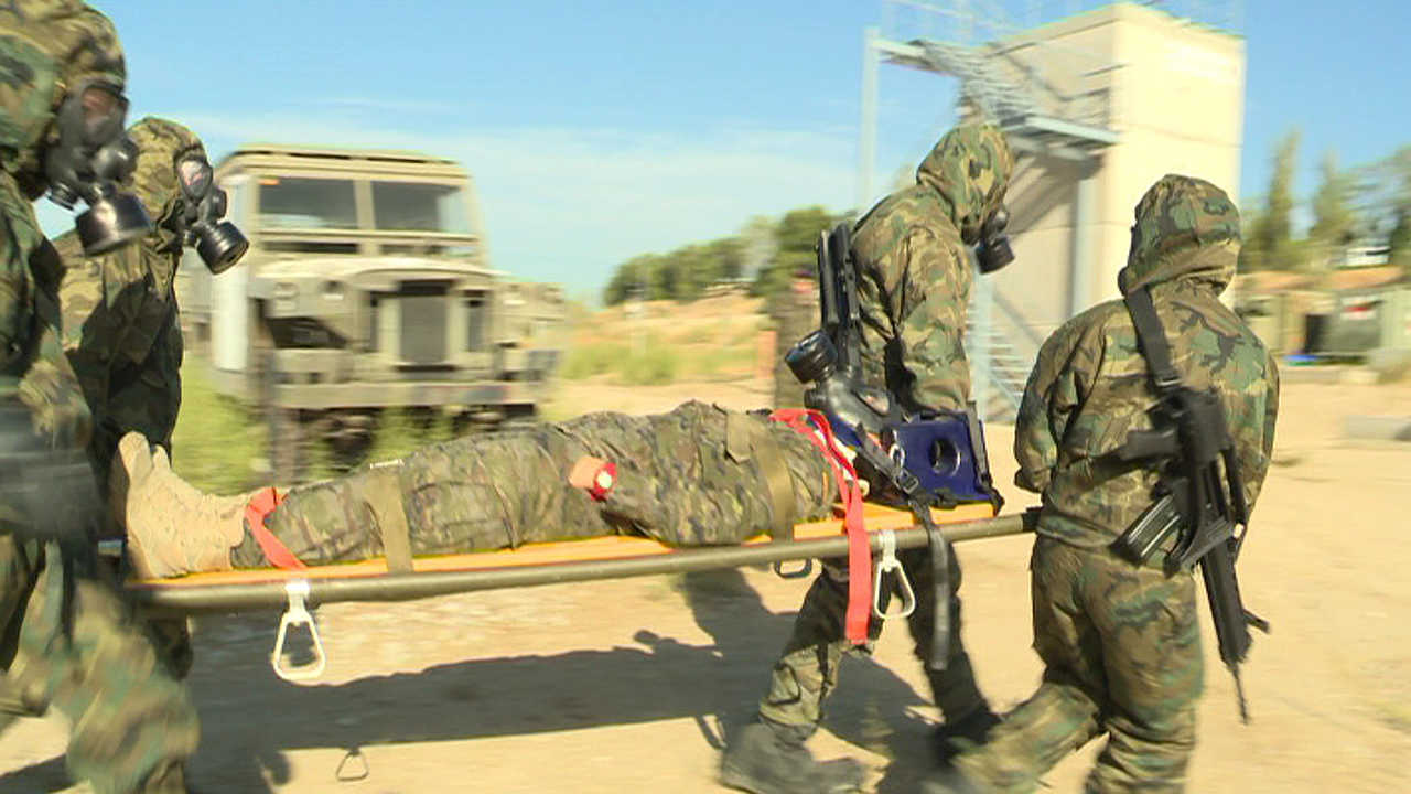 Cuatro soldados sanitarios evacúan a un soldado intoxicado con tóxicos