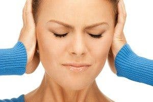 Una mujer con los ojos cerrados se tapa los oídos. Efesalud.com