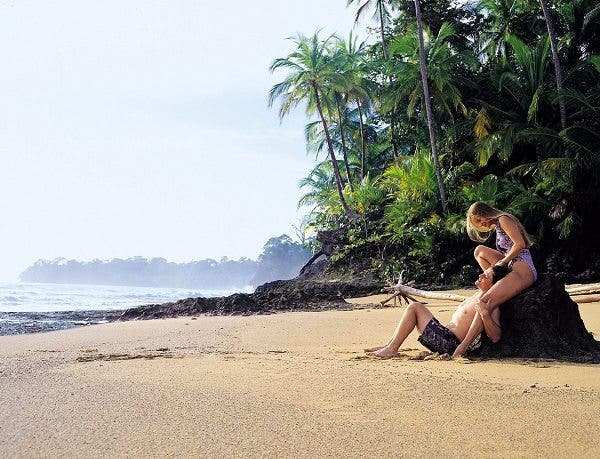 Una pareja abrazada y apoyada en una roca en una playa del Caribe. Efesalud.com