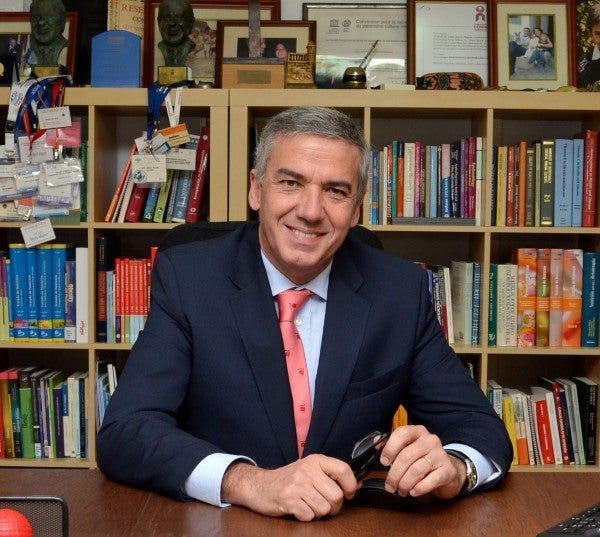 El investigador en nutrición Luis Serra posa sentado ante la mesa de su despacho con una librería al fondo repleta de libros, fotos y acreditaciones de congresos.
