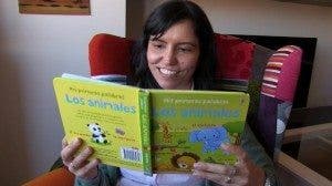 María Salmerón Ruiz, pediatra del Hospital La Paz, está sentada en un sillón con orejeras y lee un libro, de color mostaza, ilustrado con animales, que suele deletrear a su hija Julia, de un año de edad