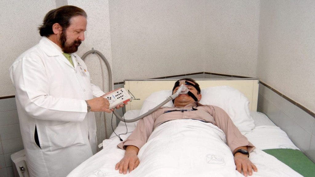 Un médico comprueba las constantes vitales de un paciente monitorizado para analizar los trastornos del sueño.