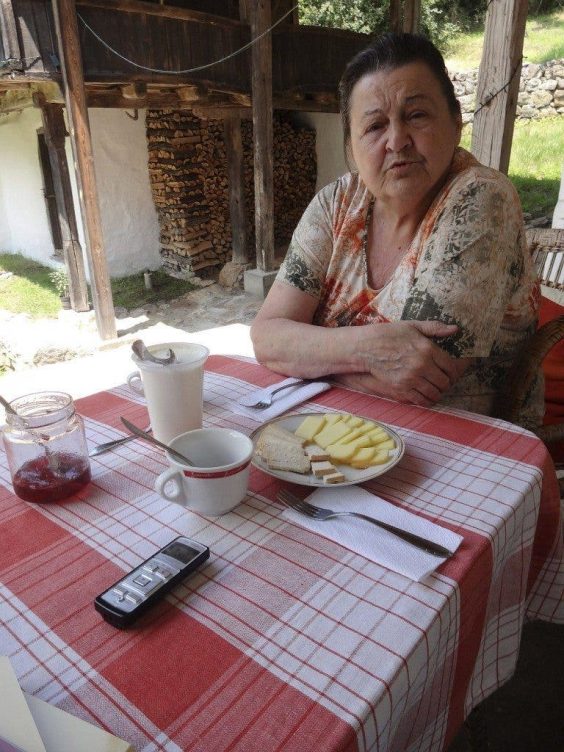 La nieta del descubridor de las propiedades del yogur sentada a la mesa con queso, mermelada y yogur búlgaro.