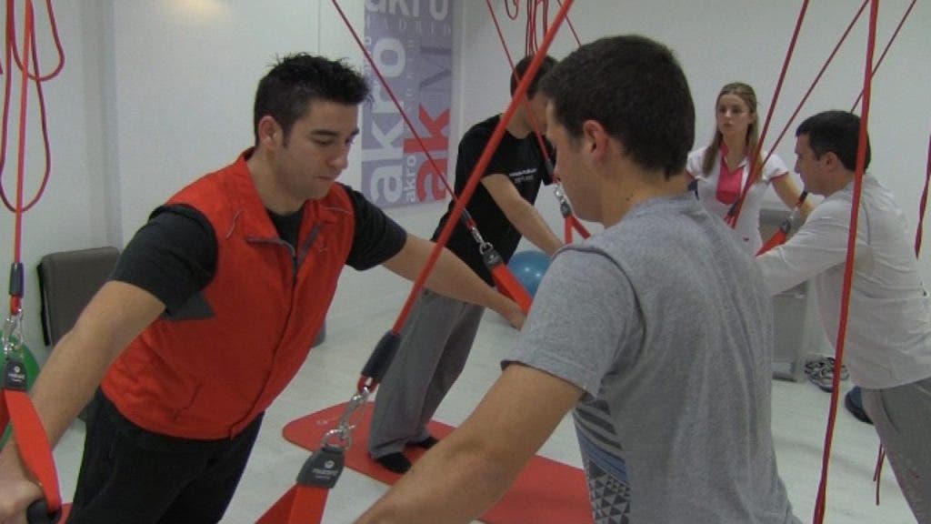 Un grupo de jóvenes realiza ejercicios con la técnica Redcord, cuerdas colgadas a las que se agarran con asideros para fortalecer su estructura músculo esquelética