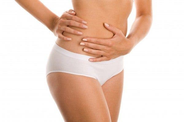 Imagen que muestra únicamente desde la cintura hasta la mitad de los muslos de una mujer con braguita blanca que rodea con sus manos su cintura. Efesalud