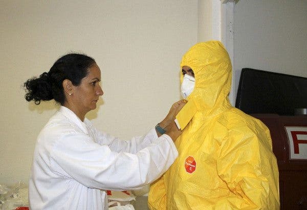 Una sanitaria ayuda a otro profesional a ponerse el traje para tratar a un enfermo con ébola. Efesalud.com