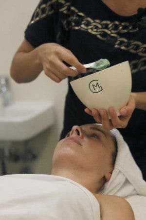 Una mujer tumbada en una camilla espera recibir un tratamiento facial.