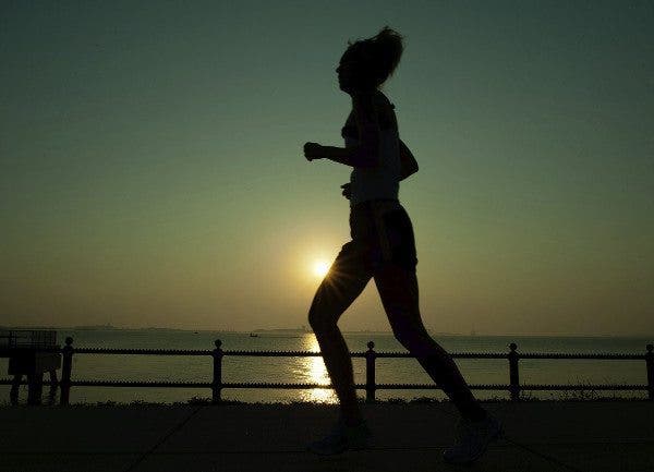 Una mujer corriendo y al fondo puesta de sol. Efesalud.com