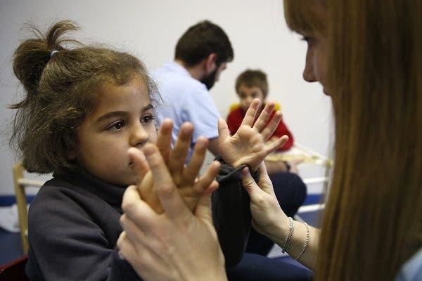 Manuela, en primer plano, y su hermano Pablo, al fondo, con los psicólogos en una clase de estimulación cognitiva para intentar frenar la demencia que produce el síndrome de Sanfilippo. EFE/Javier Mariscal