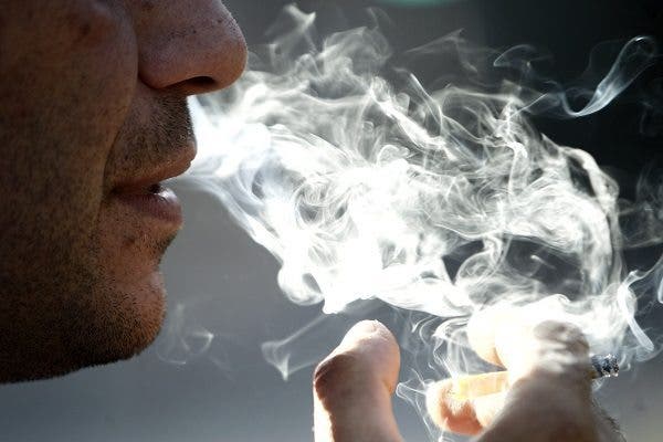 Un hombre expulsando el humo de un cigarro